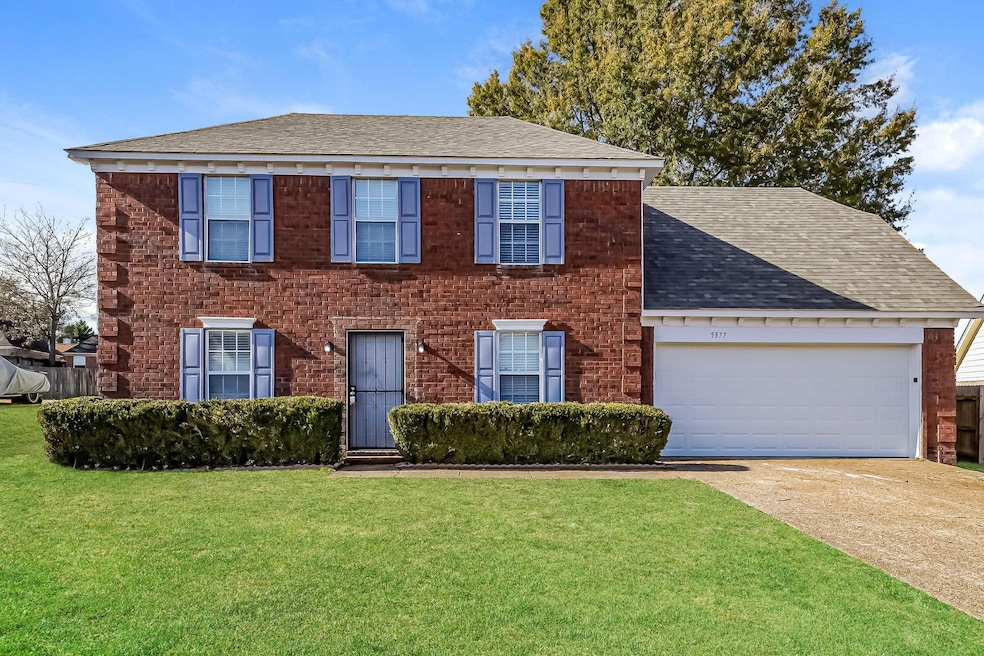 Colonial house featuring roof with shingles, driveway, an attached garage, and a front lawn