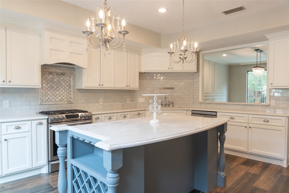 This elegant kitchen features white cabinetry, a l