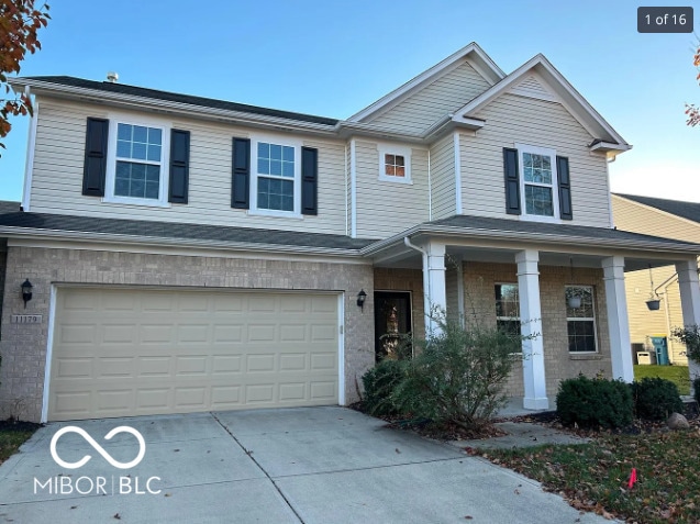 traditional home with a porch, an attached garage, brick siding, and concrete driveway