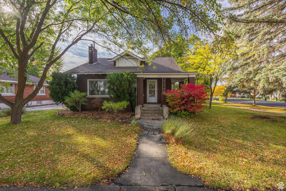 Bungalow featuring a front yard, a chimney, covered porch.