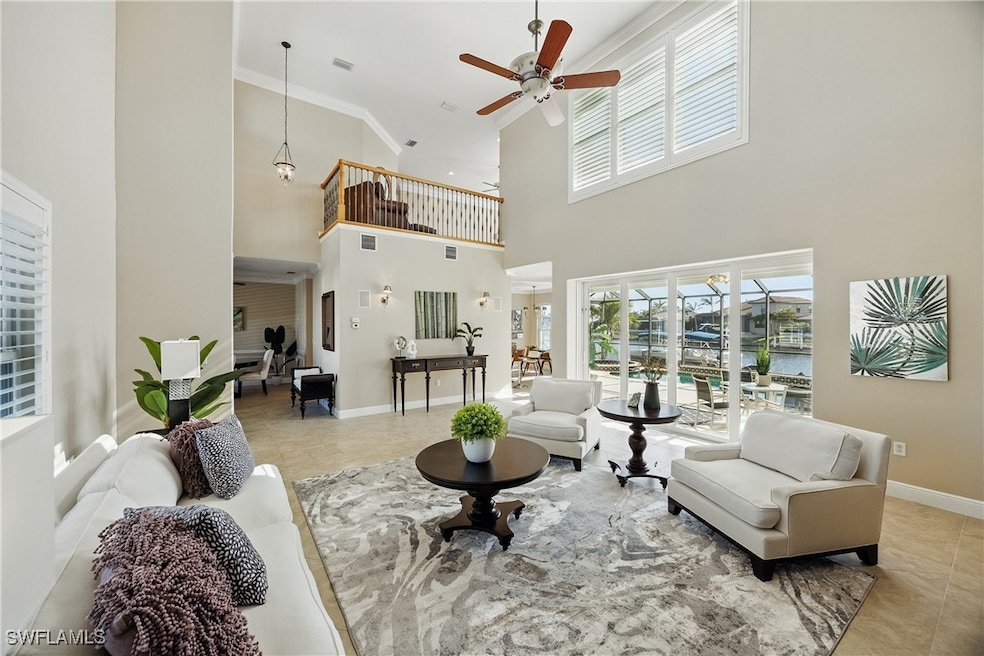 Living room featuring a towering ceiling, a ceiling fan, tile patterned flooring and ornamental molding