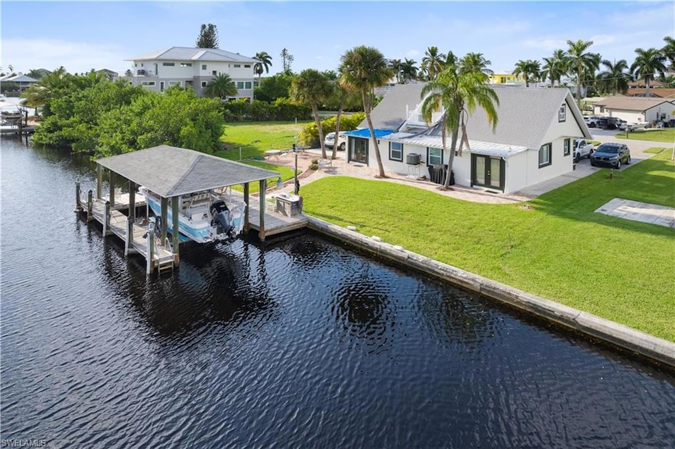 View of dock with a patio, a water view, and a lawn