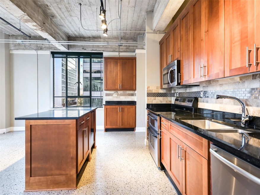 Kitchen with dark stone counters, a sink, stainle