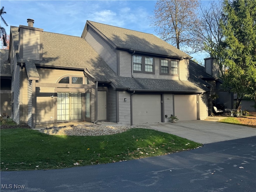 Traditional home with concrete driveway, a chimney, a garage, and a shingled roof