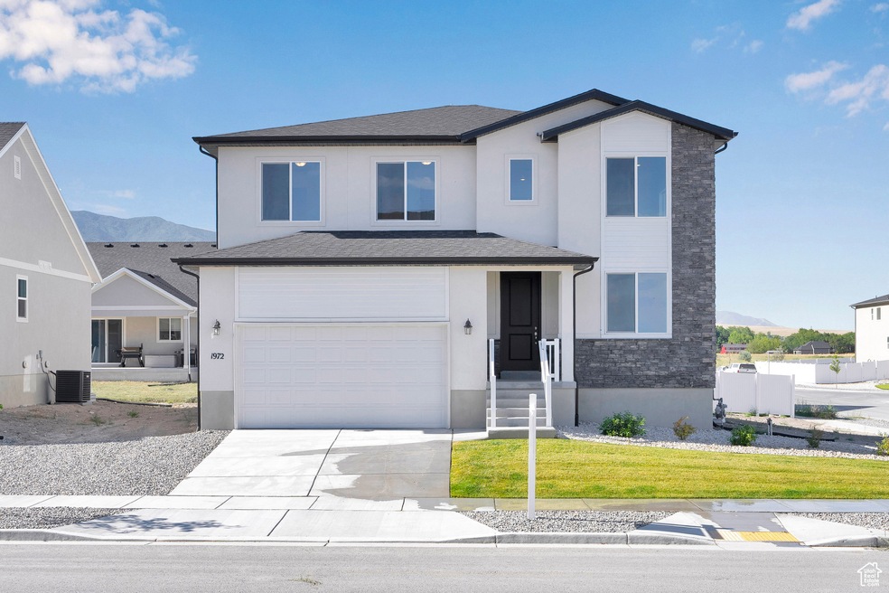 View of front of house featuring concrete driveway, a mountain view, a garage, stucco siding, and a front yard