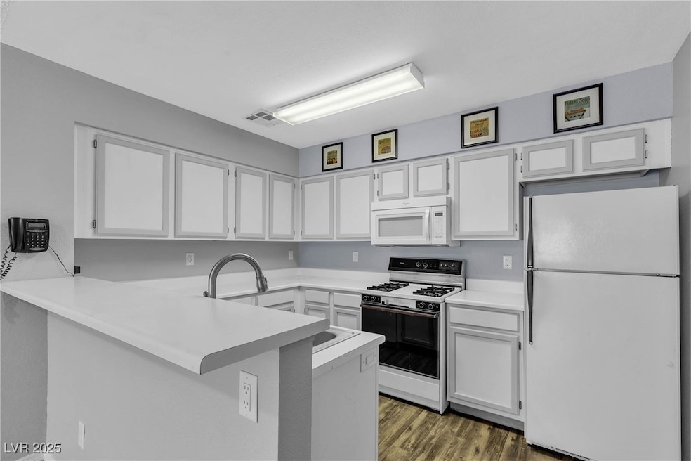 Kitchen featuring white appliances, a peninsula, w