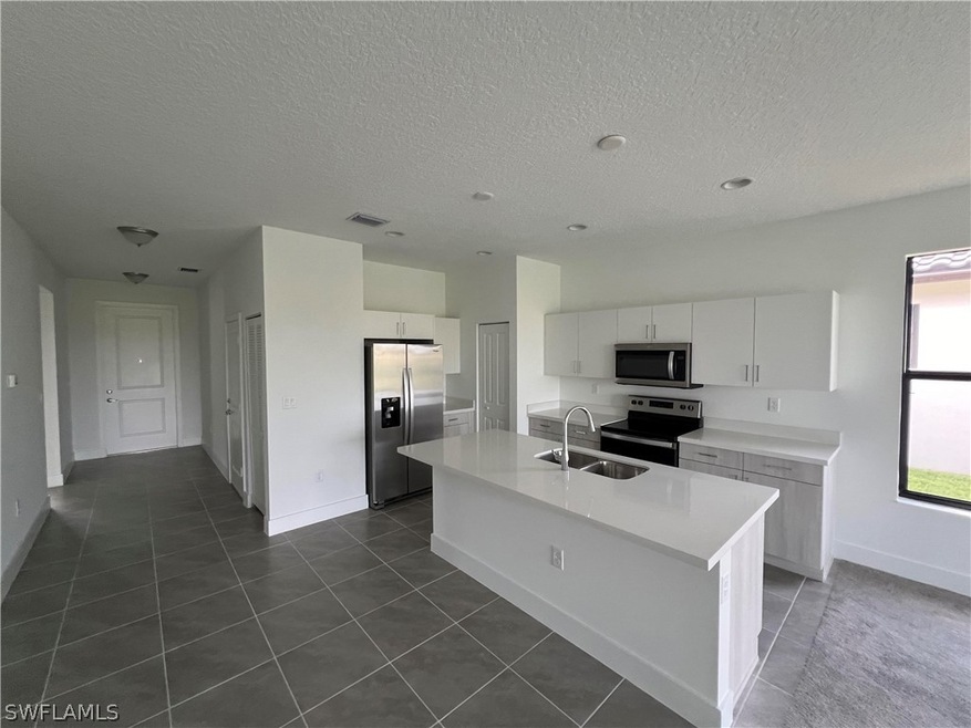 Kitchen with white cabinetry, an island with sink,