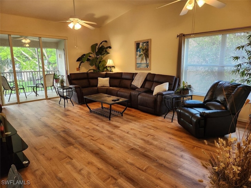 Living room featuring vaulted ceiling, ceiling fan, and light hardwood / wood-style floors
