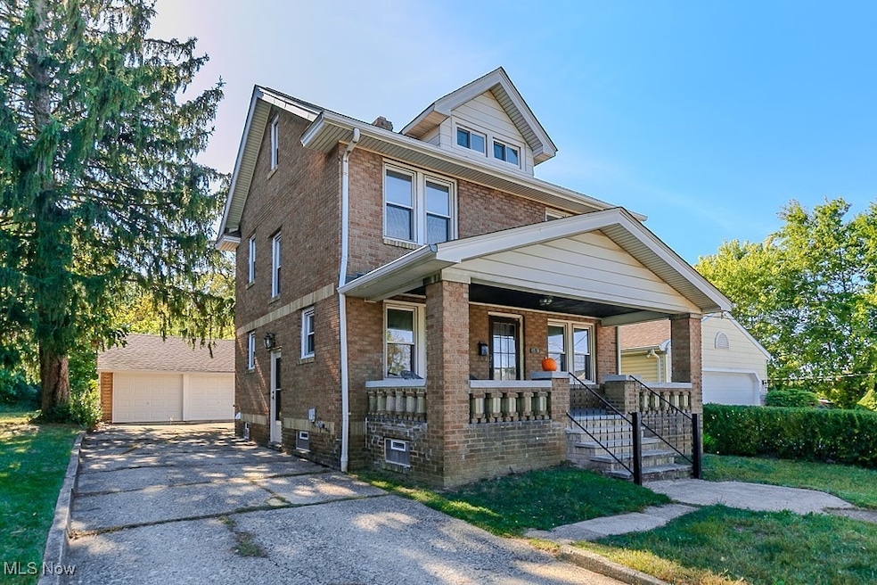 Traditional style home featuring a porch, brick siding, a detached garage, and an outdoor structure