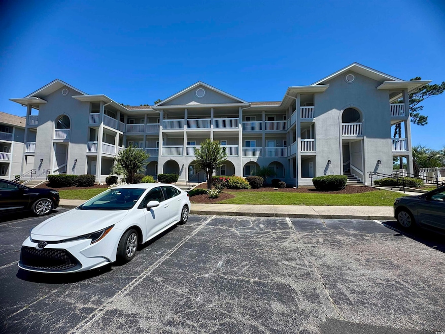 View of apartment building / complex featuring uncovered parking