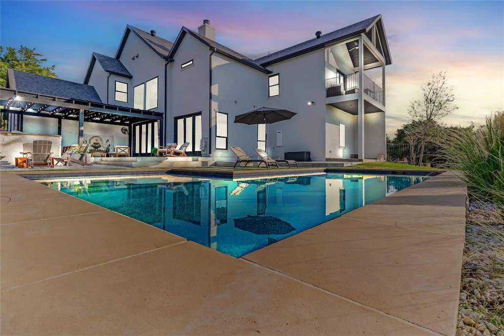 Pool at dusk with a fireplace and a patio