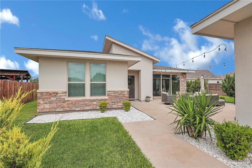 Rear view of property featuring stucco siding, stone siding, and a patio area