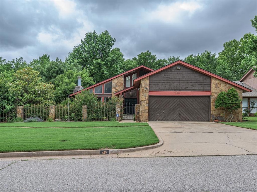 View of front of house with stone siding, a garage, and driveway