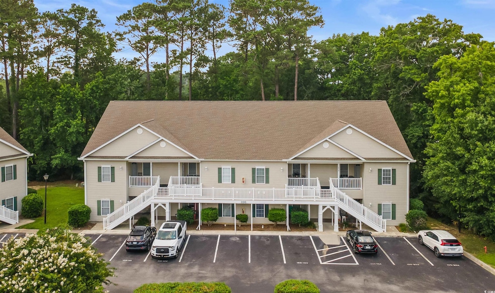 View of property featuring stairs and uncovered parking
