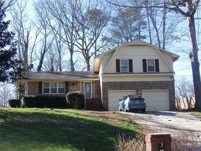Dutch colonial with brick siding, concrete driveway, a garage, a front yard, and a gambrel roof