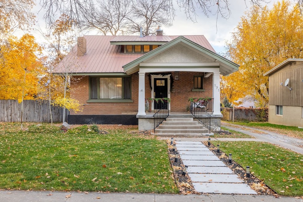 View of front facade with a porch, a metal roof, a chimney, and brick siding