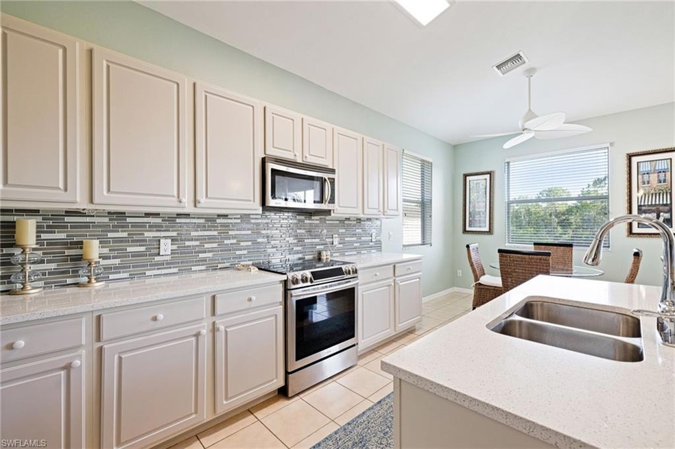 Kitchen with appliances with stainless steel finishes, light tile patterned flooring, backsplash, a ceiling fan, and light stone countertops