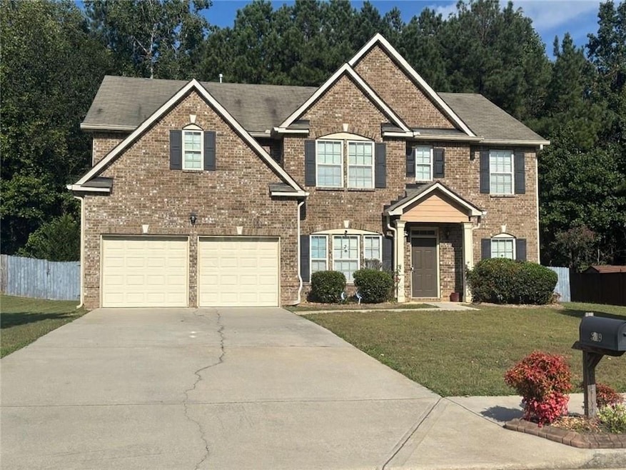 View of front facade featuring driveway, brick siding, and an attached garage.