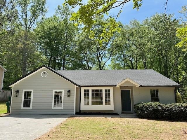 Single story home featuring driveway and a front y