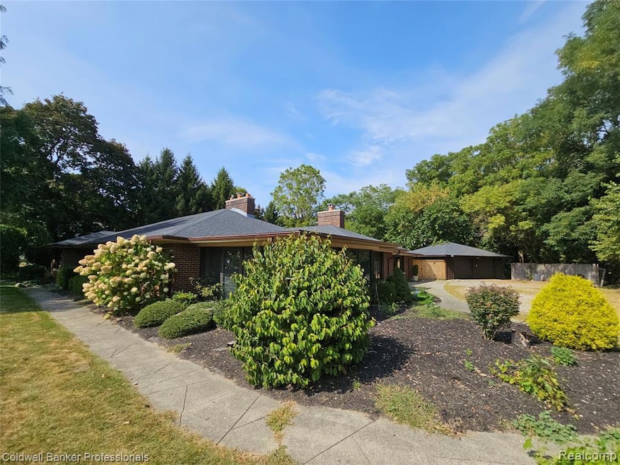 View of front of property with a chimney, brick siding, and view of wooded area