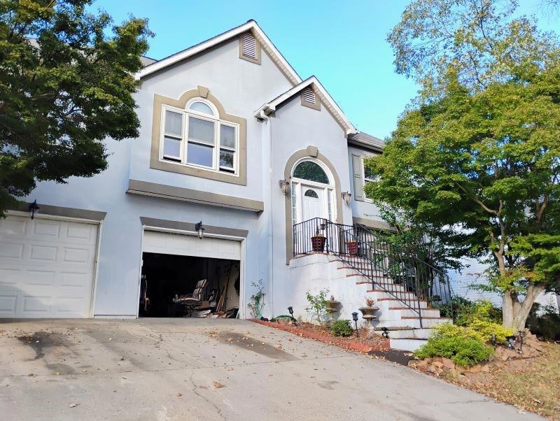 View of front facade featuring stucco siding, an attached garage, and driveway