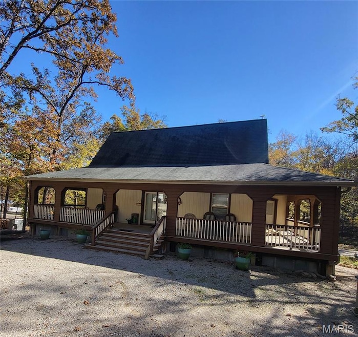 View of front facade with a large porch and a shingled roof