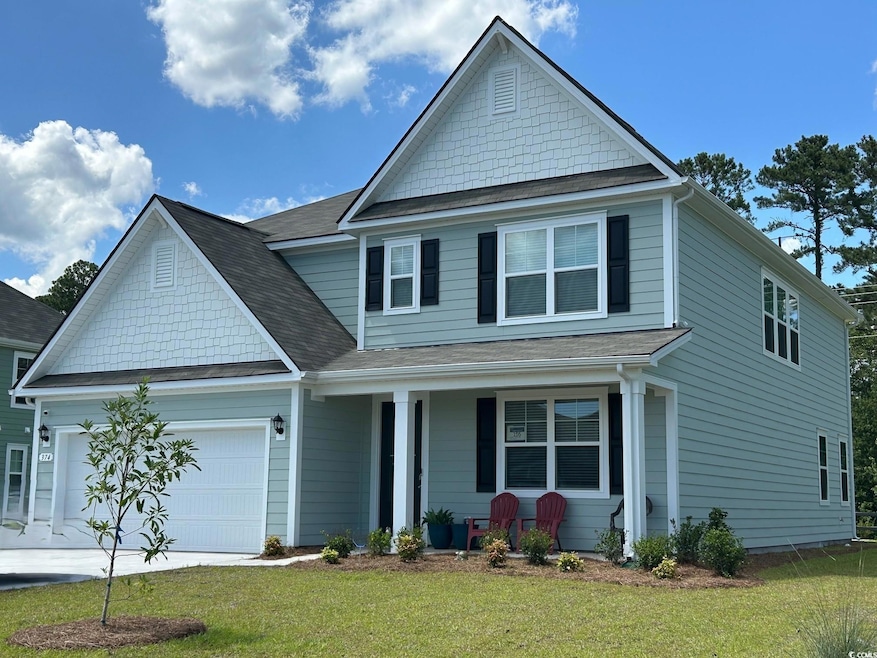 Traditional-style home with a porch, a front lawn, a garage, and a shingled roof