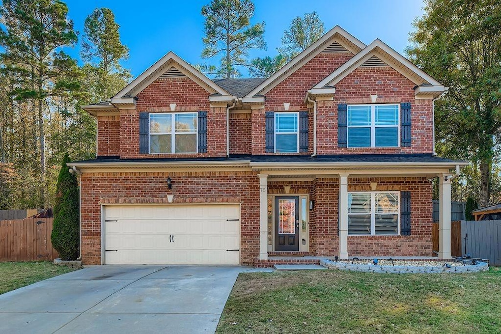 View of front of house featuring covered porch, brick siding, a garage, and concrete driveway