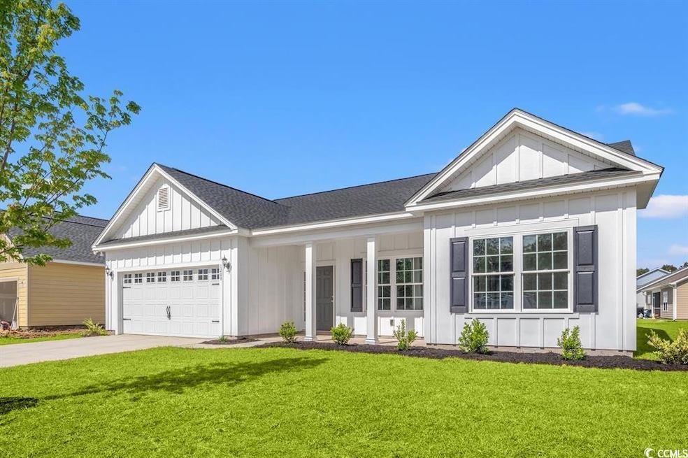 View of front of house featuring board and batten siding, an attached garage, a front lawn, driveway, and a porch