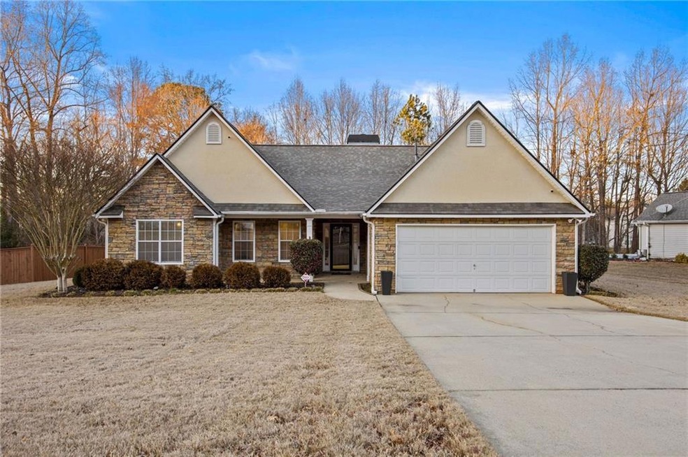 Traditional home with driveway, stone siding, a ga