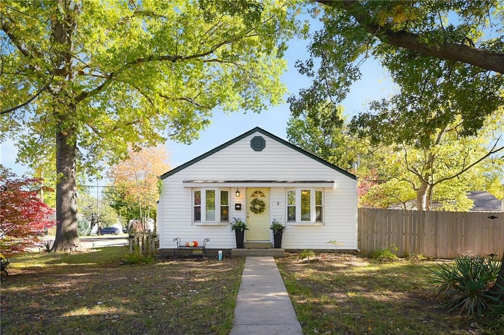 Charming single-level home with white siding, green trim, and mature shade trees.