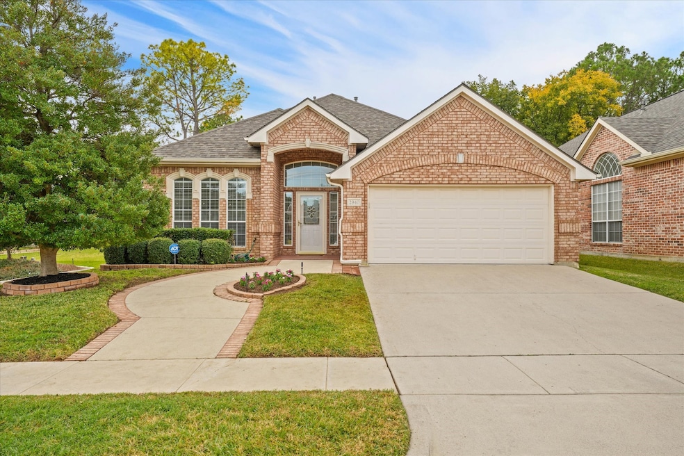 View of front of home with a shingled roof, brick siding, concrete driveway, and a front lawn