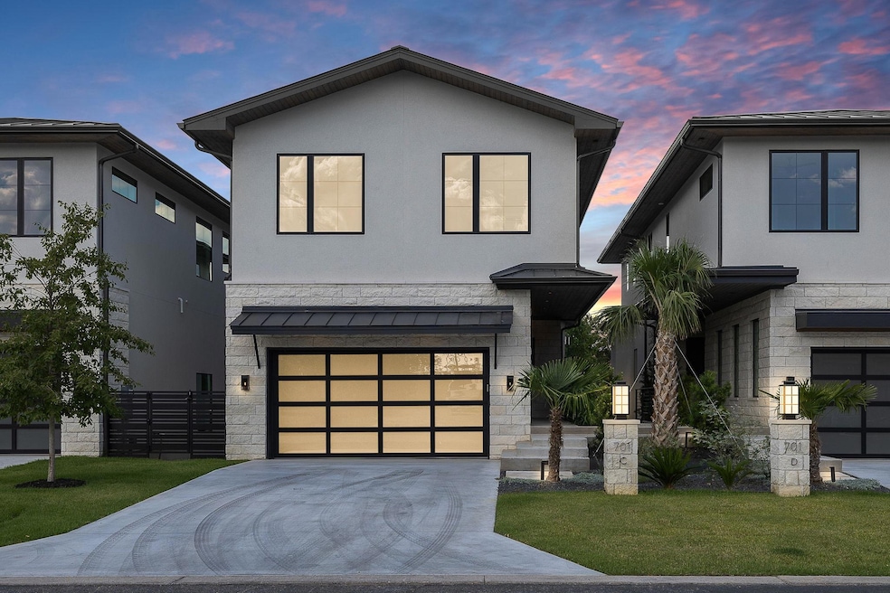Contemporary home featuring stone siding, stucco siding, driveway, and a lawn