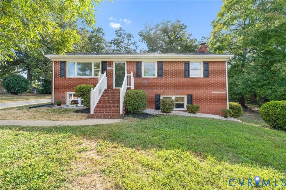 Split foyer home featuring brick siding, a chimney, and a front lawn