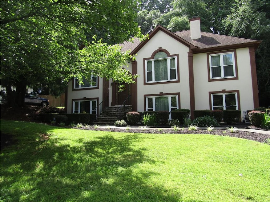View of front of house featuring stucco siding, a chimney, a front lawn, and roof with shingles