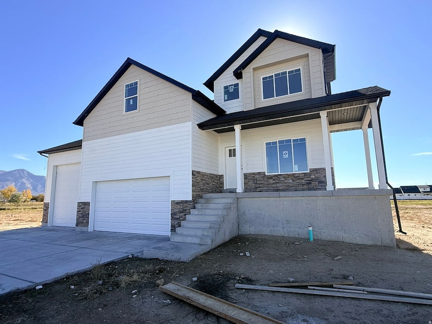 View of front of property with stone siding, covered porch, a garage, and concrete driveway