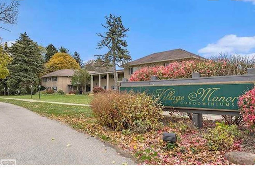 Beautifully maintained exterior showcasing mature landscaping, classic brick architecture, and the welcoming entrance to Stratford Village Manor. Attractive curb appeal sets the tone for a quiet, well-kept community