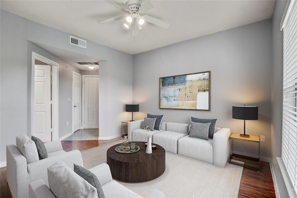 Living area with ceiling fan, baseboards, and woo