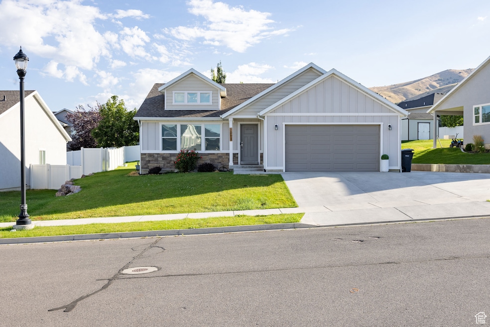 View of front of home featuring board and batten siding, driveway, an attached garage, stone siding, and a shingled roof