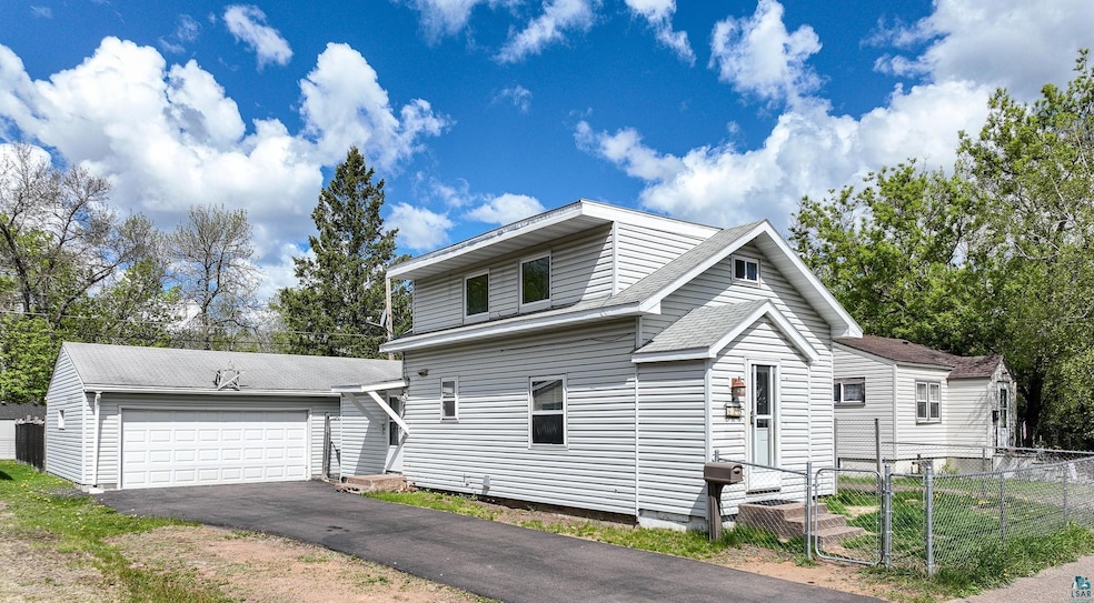 View of front of property with cooling unit, roof with shingles, and a detached garage