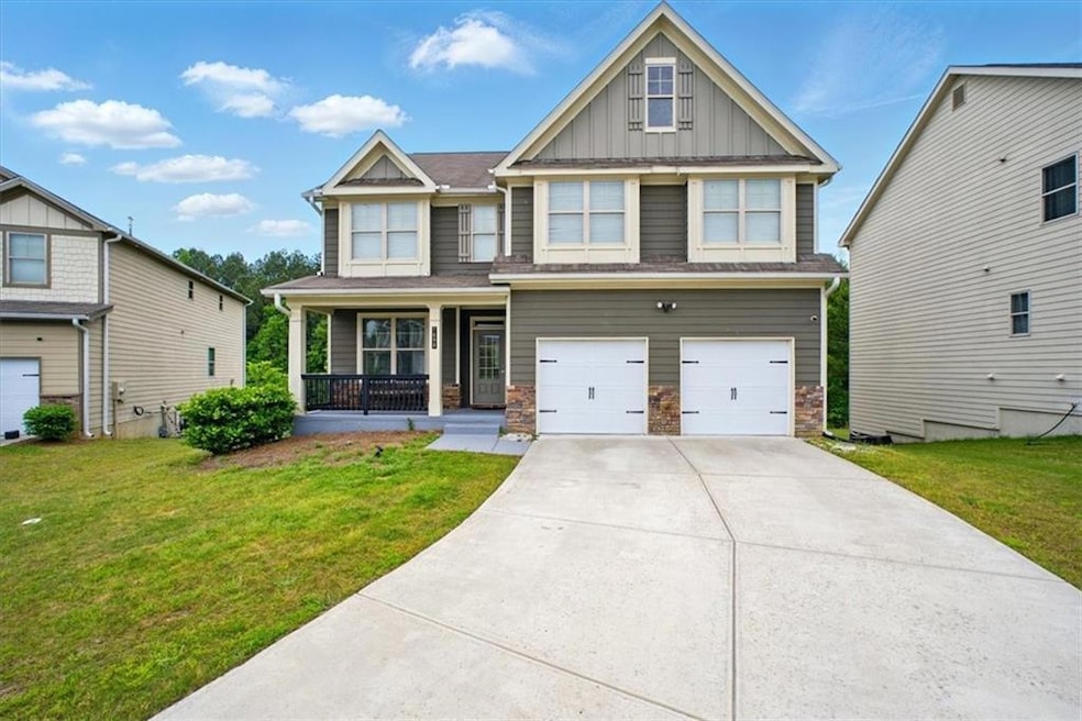 Craftsman house with board and batten siding, covered porch, an attached garage, a front yard, and concrete driveway