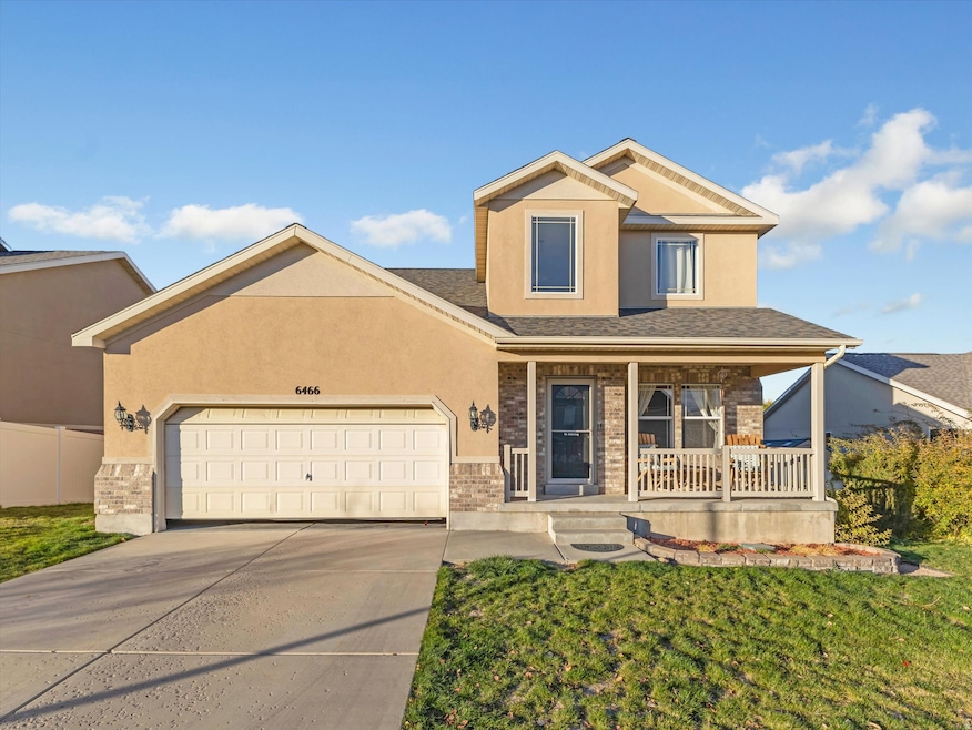 View of front of house featuring covered porch, brick siding, a garage, driveway, and stucco siding
