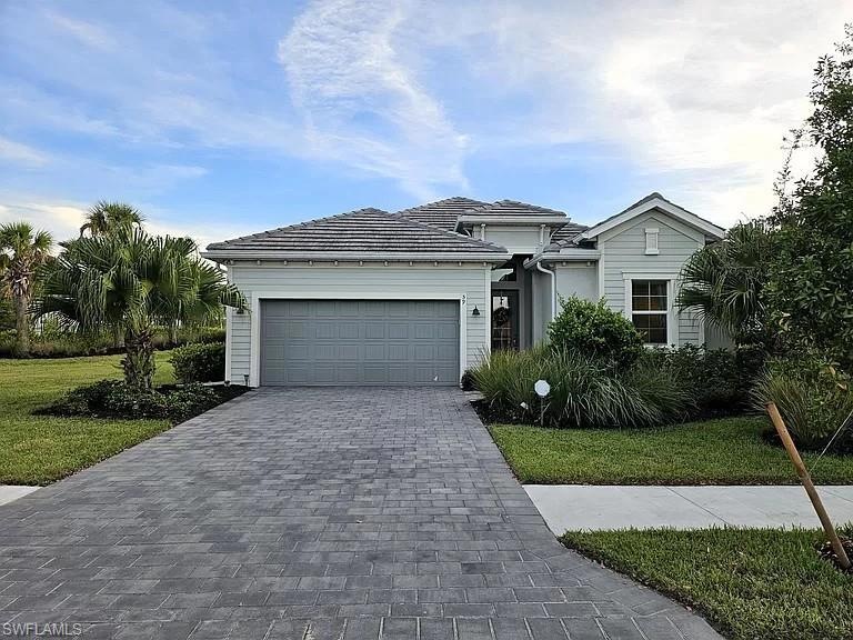 View of front of property with an attached garage, decorative driveway, and a front yard