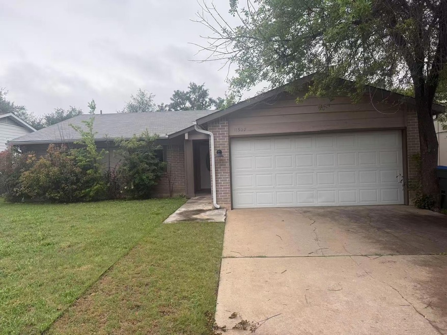Single story home featuring driveway, brick siding, a garage, and a front yard