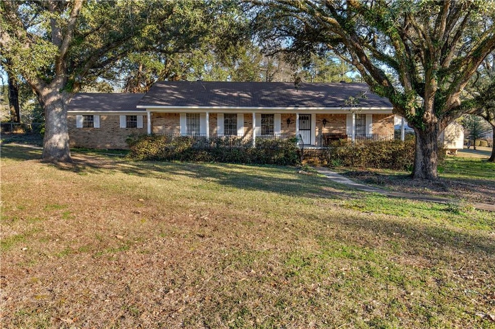 Ranch-style home featuring a front lawn, brick siding, and a porch