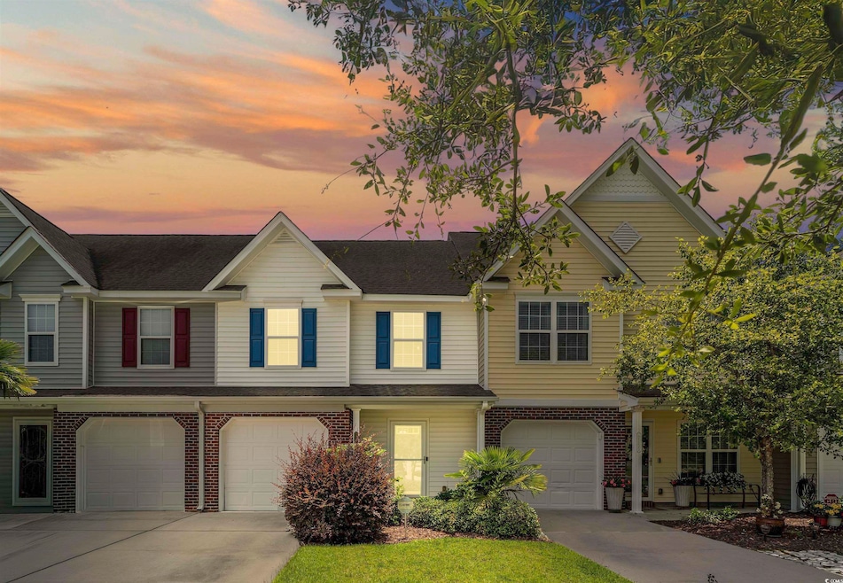 Townhome / multi-family property with a garage, driveway, brick siding, and a shingled roof