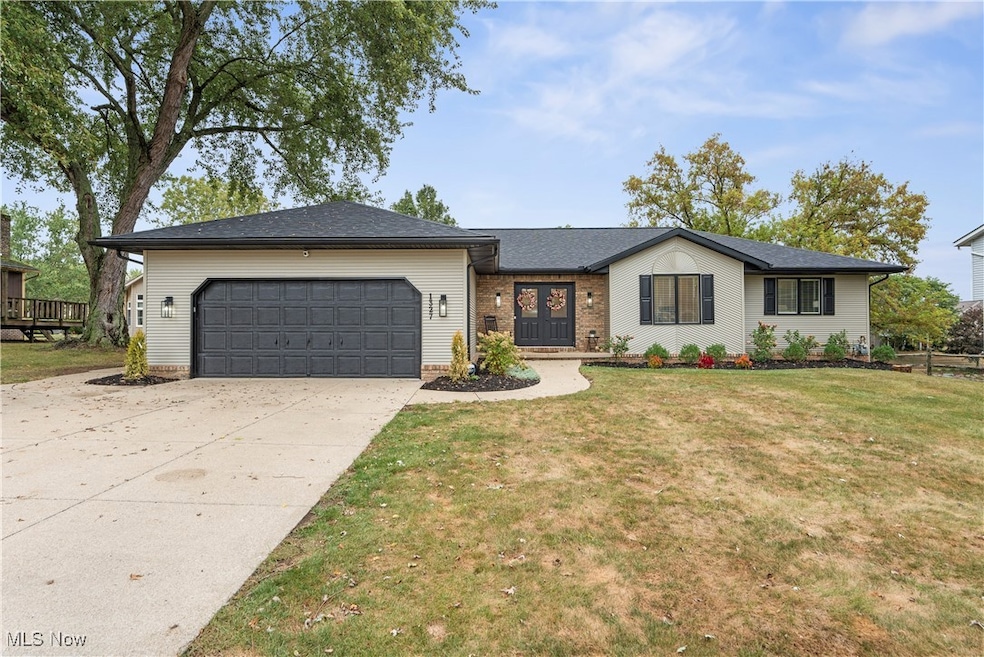 Ranch-style house with a front lawn, concrete driveway, a garage, a shingled roof, and brick siding