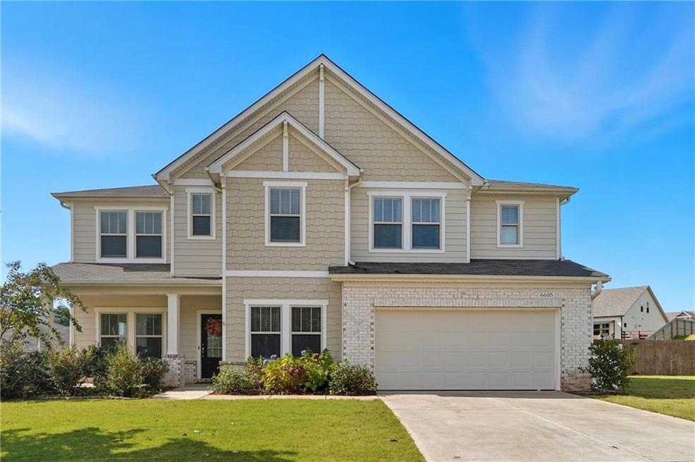 Craftsman-style house featuring a front lawn, a porch, concrete driveway, brick siding, and a garage