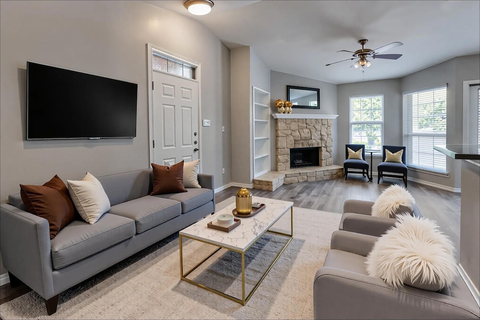 Living area with ceiling fan, wood finished floors, a fireplace, and built in shelves