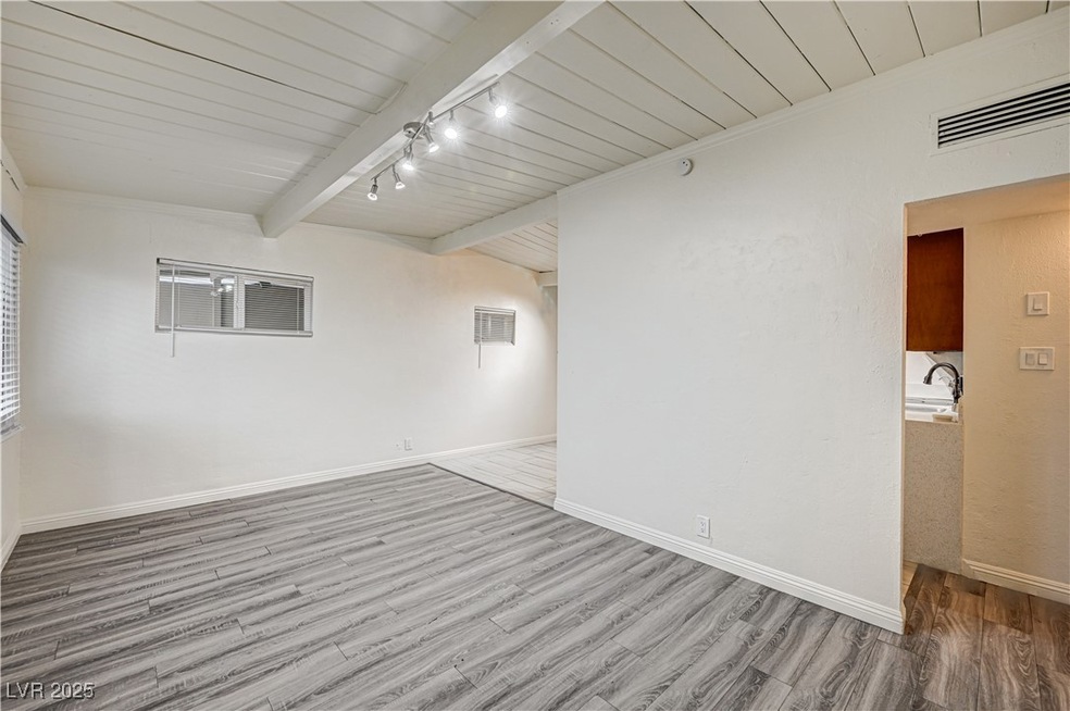 Spare room with beam ceiling, wood finished floors